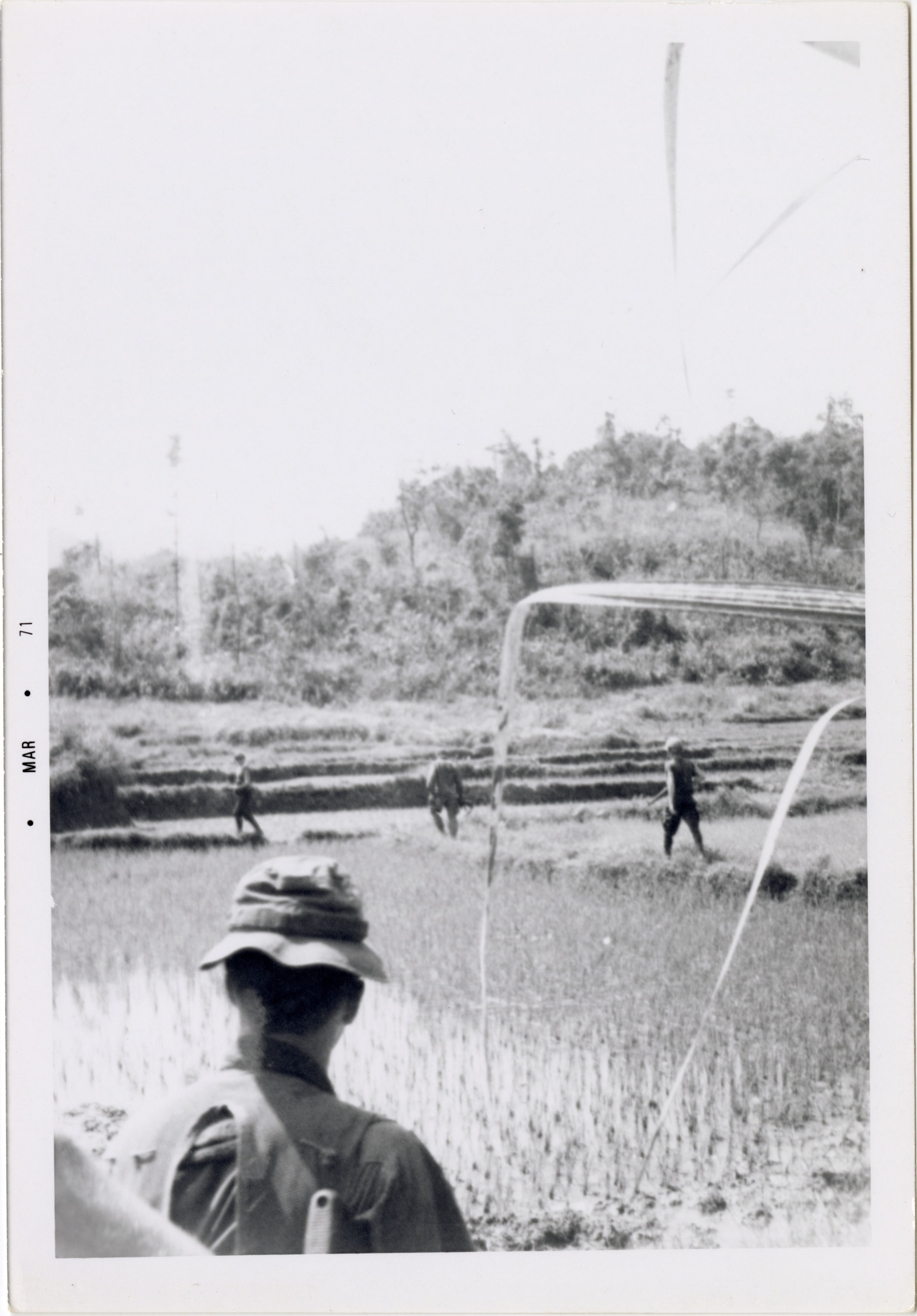 Four soldiers are walking around in the Vietnam countryside.