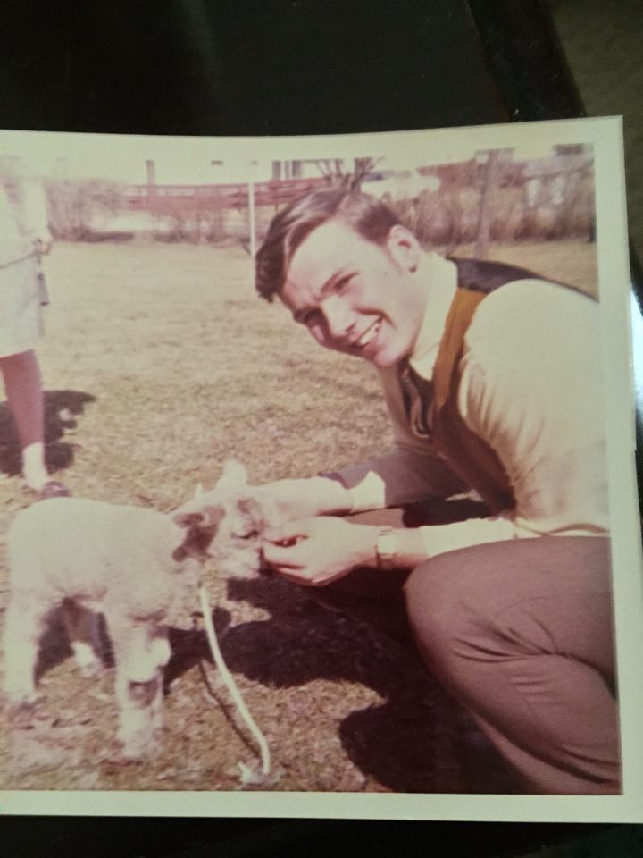 A younger Terry, prior to shipping out to Vietnam, poses with a small baby goat while staring into the camera and smiling.