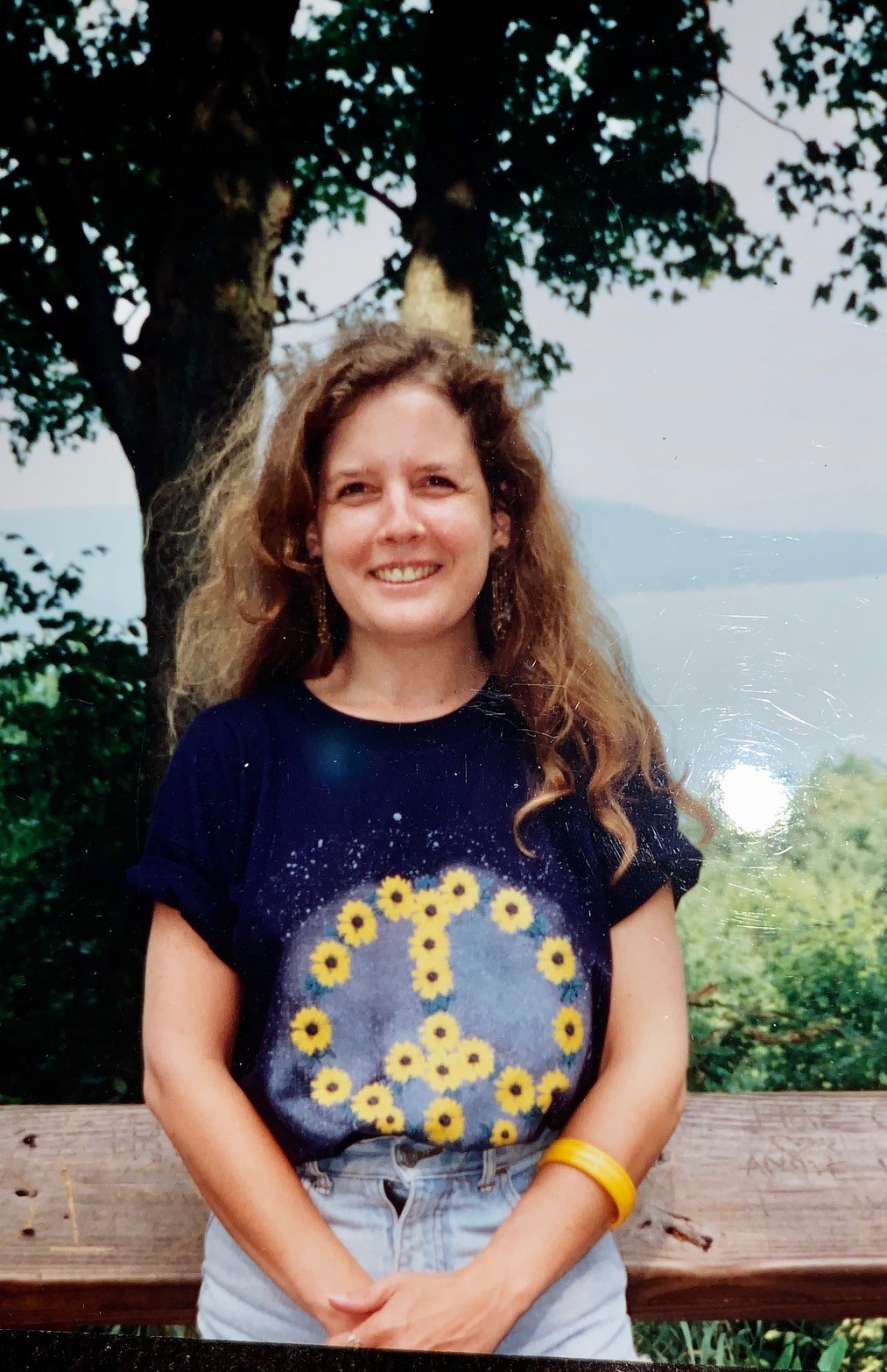 Terry Smith's niece, Donna Murphy, wears a shirt with a peace sign made out of flowers while smiling into the camera.